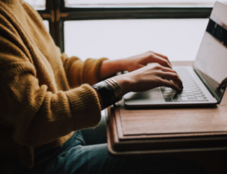 Manos posadas sobre el teclado de una computadora portátil