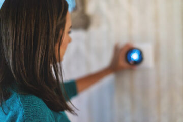 woman adjusting smart thermostat