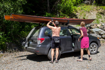 Personas que salen del lago Spada con kayaks de madera