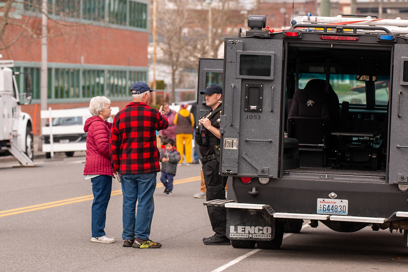 一名警察向一对夫妇展示警用 Bearcat 卡车的内部