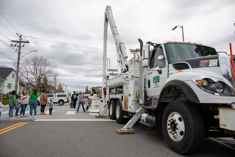 A crowd waits to take their turns in the bucket of a truck