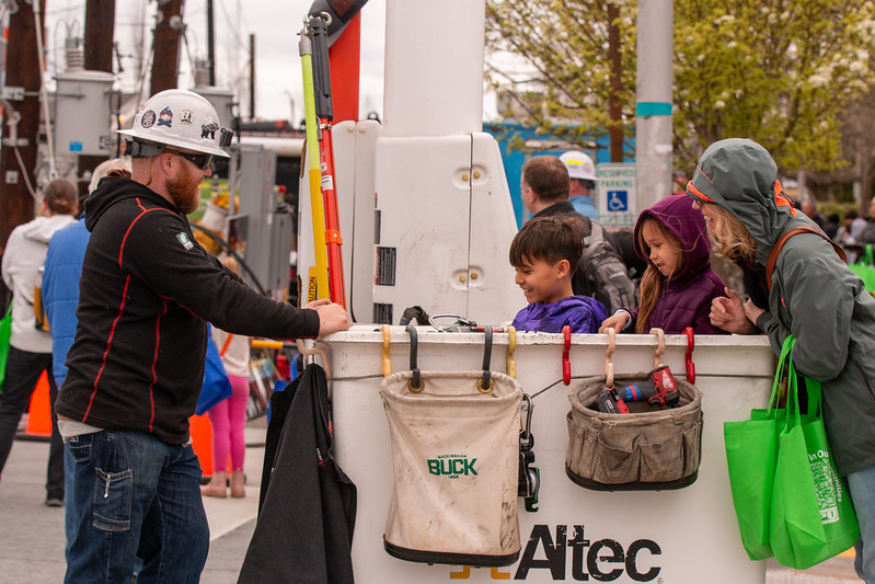 Two kiddos talking to a lineman from the bucket of a truck