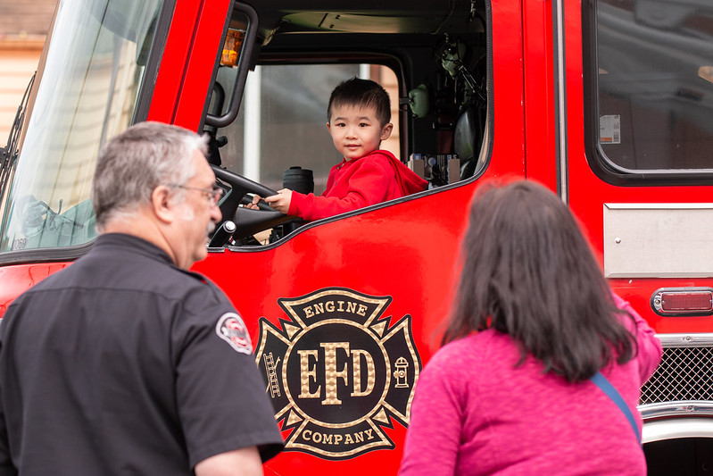 A young man sits behind the wheel of a fire truck