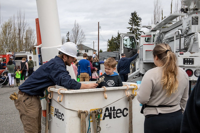A youngster stands in the bucket of a truck and learns about being a lineworker