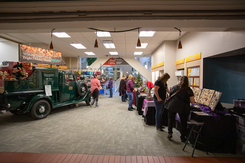 Customers shopping a holiday craft bazzar, with a vintage truck in the picture