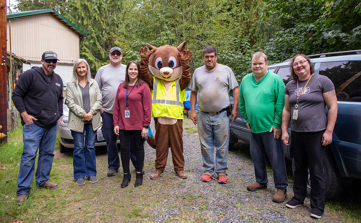 A group of people and a squirrel mascot smile at the camera