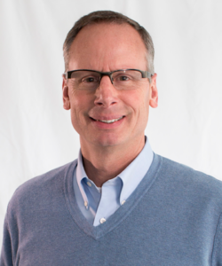 PUD CEO GM John Haarlow smiling and wearing blue sweater and shirt