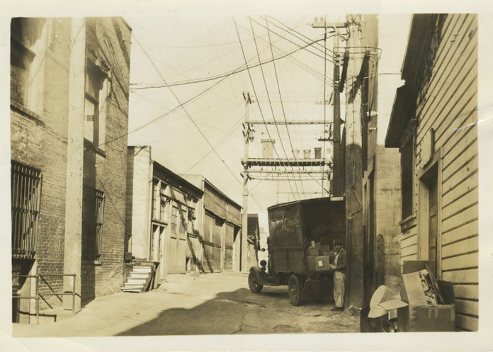 A 1930s electrical truck working on power lines in a brick alley