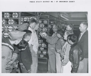 During a 1955 Open House, Meter Supervisor Arnold Nelson explains meter to boy scouts