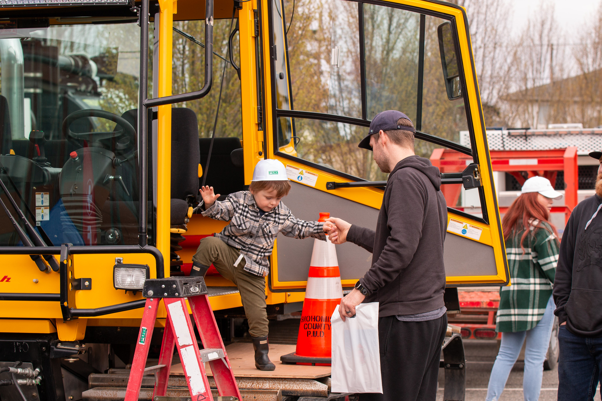 A dad helps his toddler son out of a backhoe cab