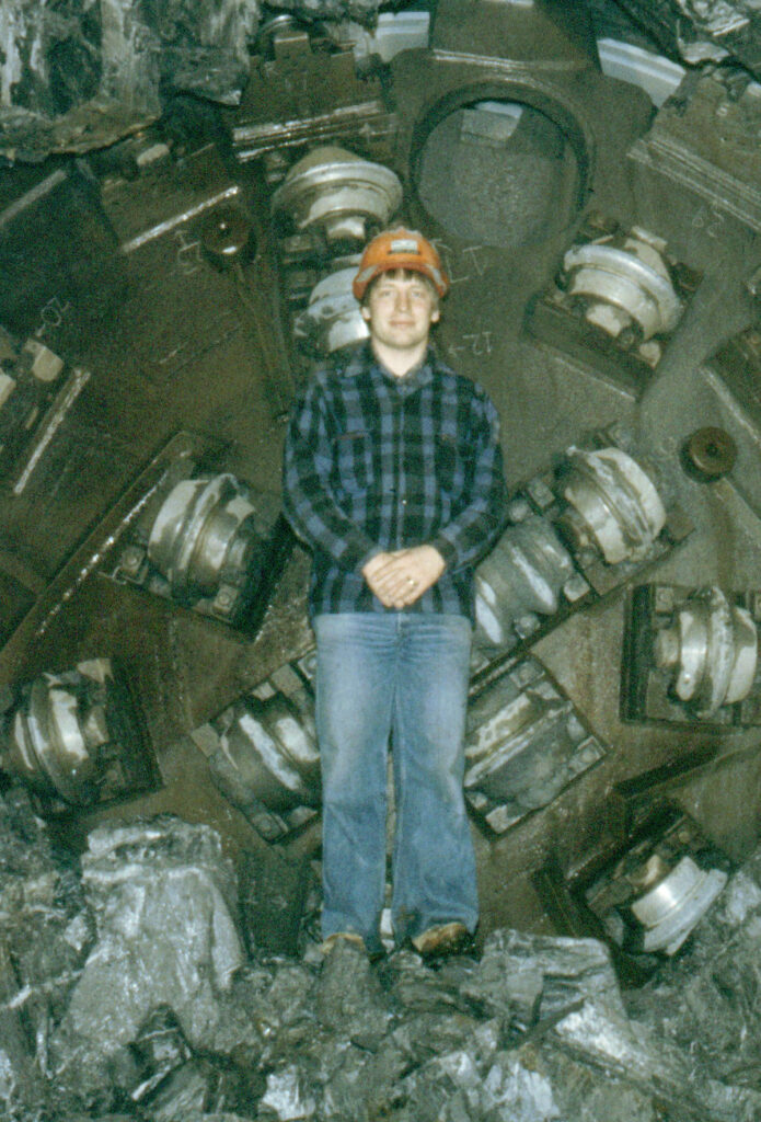 Дени Мајлс стоји испред огромне машине за бушење током изградње пројекта Џексон