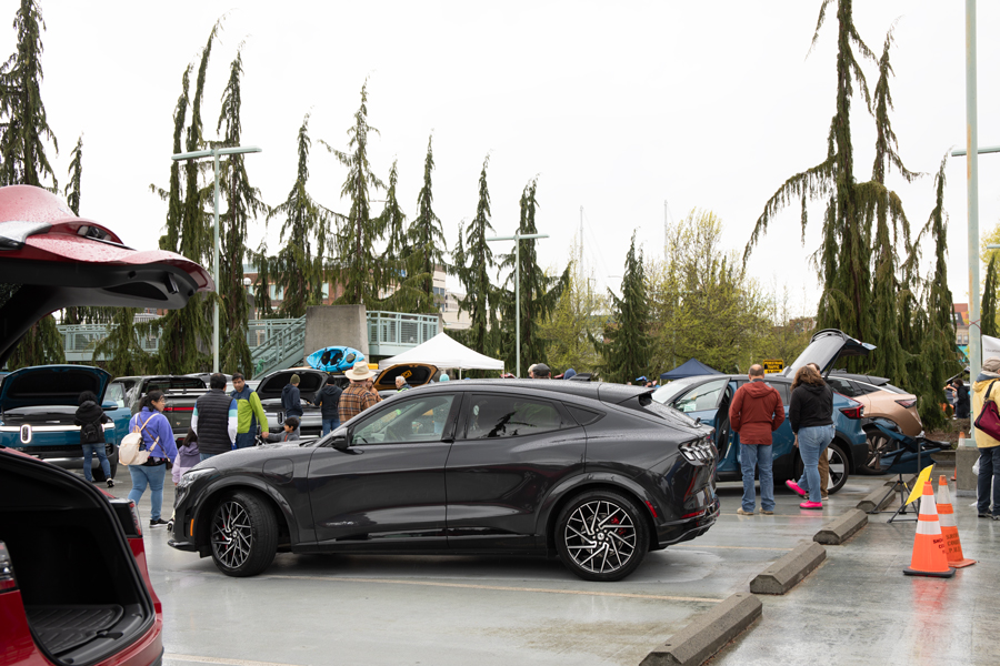 A mustang mach e sits in the foreground of this photo at the Energy Block Party EV car shot