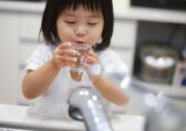 可爱的孩子享受一杯水龙头里的水