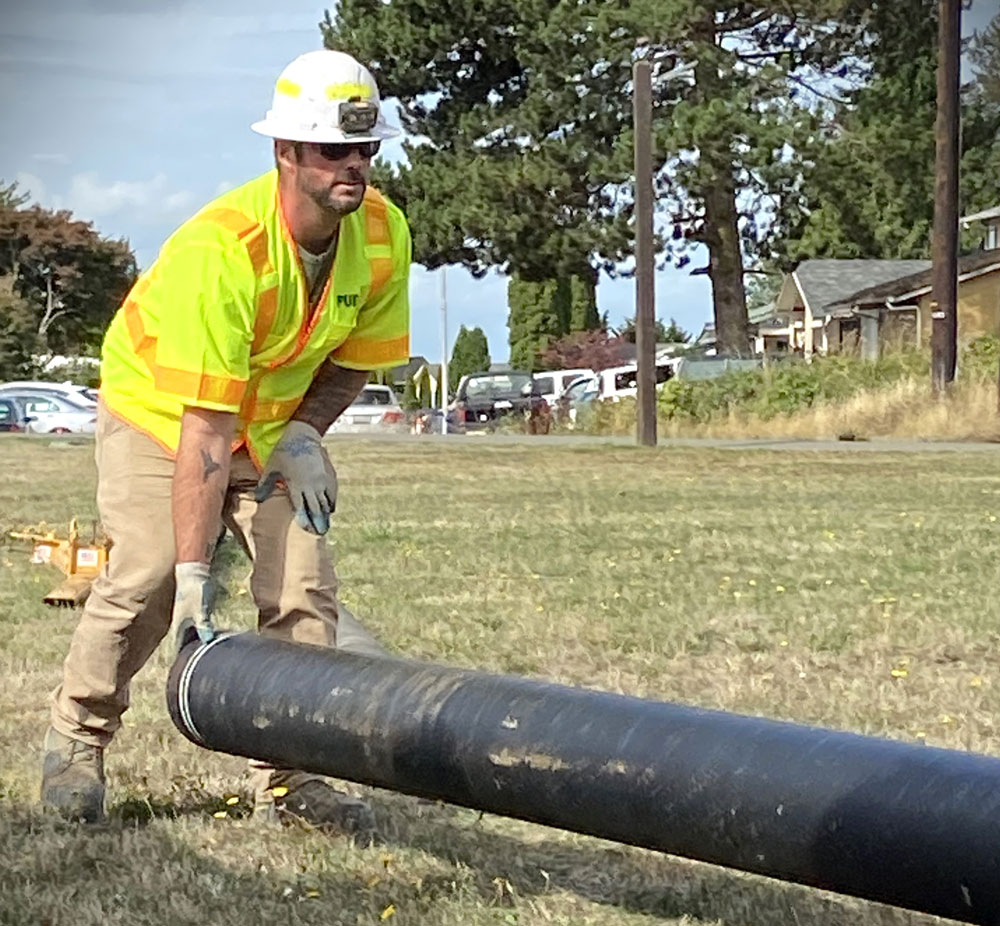 A main picks up a large black water pipe