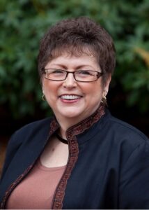 Woman smiling wearing glasses and dark jacket