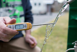A utility worker performs a water test with a digital device
