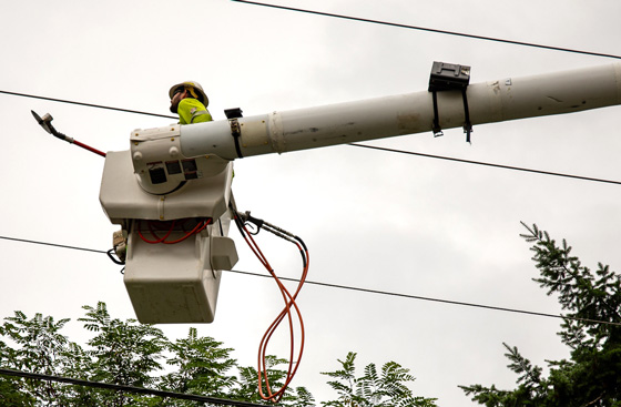 A tree trimmer in a bucket holding a long saw