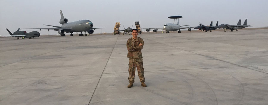 Young airman stands on the runway tarmac with an array of aircraft behind him including fighter jets