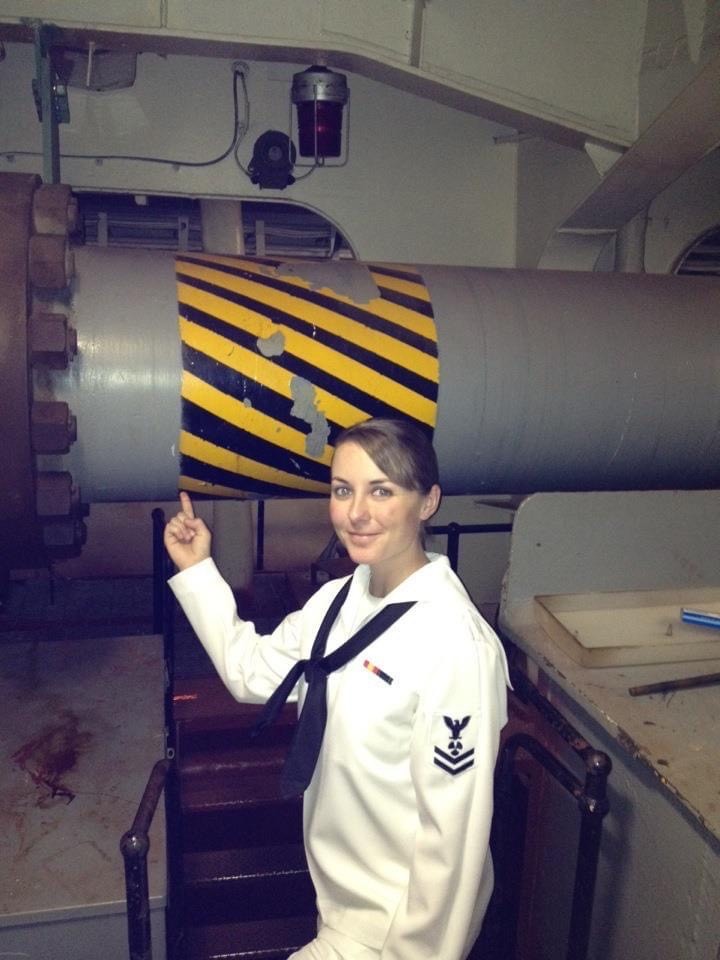 Young female US Navy sailor pointing at generating equipment