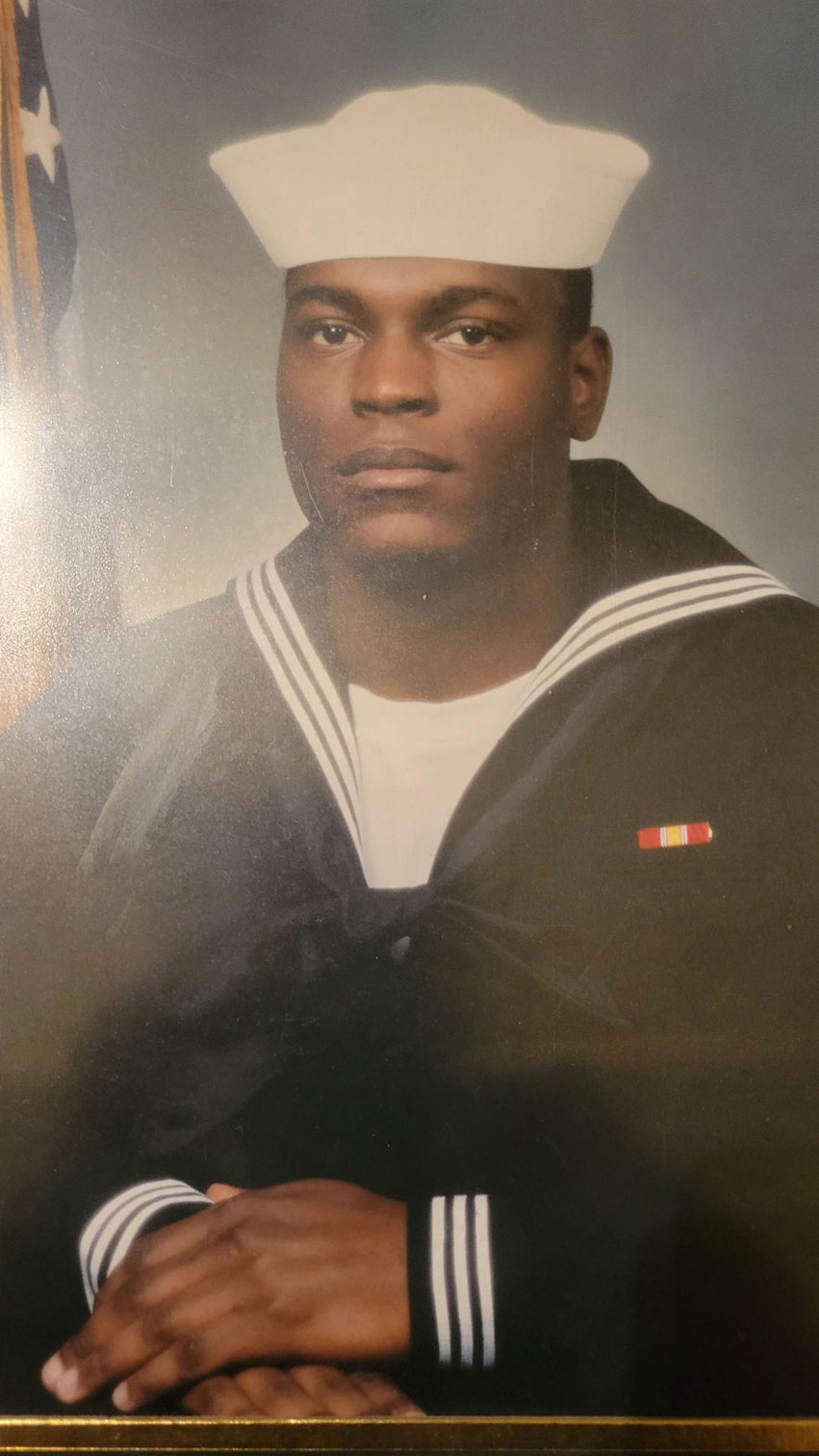 Young sailor in uniform in front of American Flag