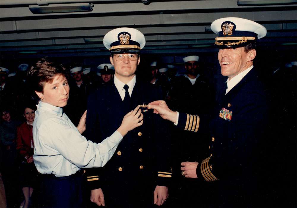 A young naval officer getting Surface Warfare pin with senior officer and his wife
