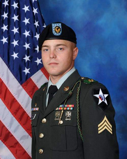 Young male US Army soldier in uniform in front of American flag