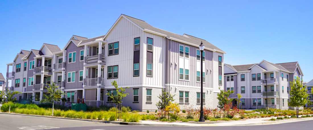 Three story modern apartment building on sunny day