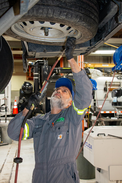 Transportation worker uses power tool on tire