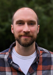 Alex Chorey, smiling in plaid shirt