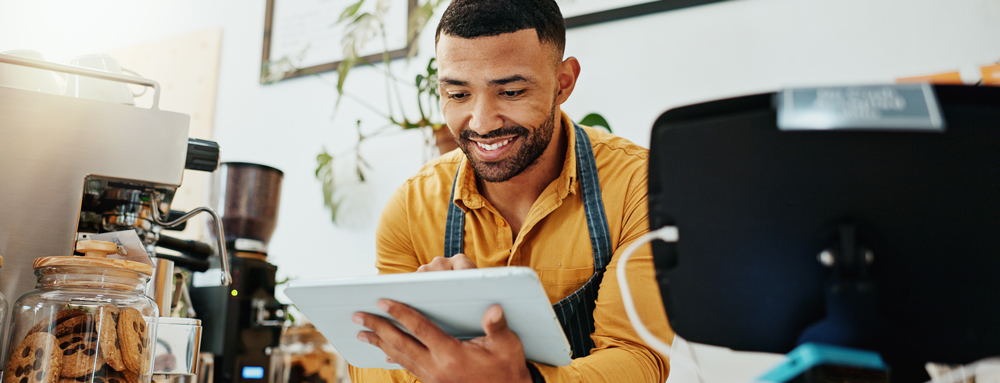 Young businessman in apron looking at tablet