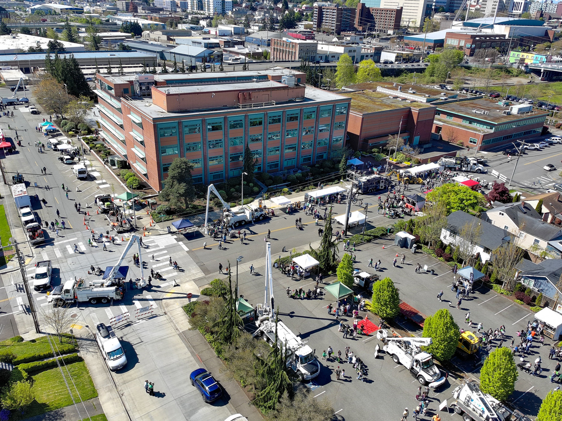 斯诺霍米什公共事业区大型砖砌建筑在能源街区派对期间的鸟瞰图。在一个美丽的春日，帐篷、大型卡车和人群聚集在建筑周围。