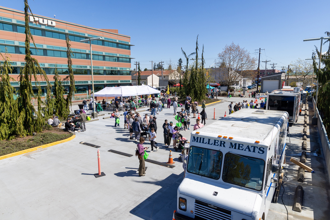 大型砖砌建筑前有停车场，上面写着“PUD”，旁边停着包括 Miller Meats 在内的餐车。