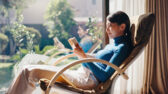 Woman relaxing in reclined chair reading in light from large windows
