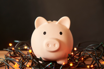 A pink piggy bank surrounded by small festive lights